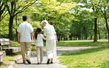 緑豊かな公園を散歩する祖父母と孫